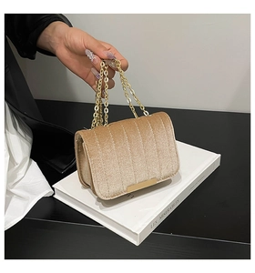 Detail of champagne velvet crossbody bag showing vertical stitching and gold metal plate