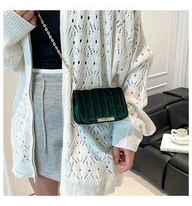 Model wearing dark green velvet crossbody bag with vertical quilting and gold chain strap
