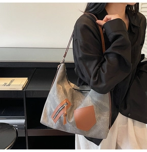 Detailed shot of gray canvas hobo bag with brown faux leather accents and zip pocket
