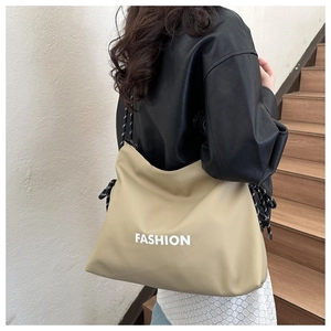 Detail of khaki PU tote bag featuring white FASHION text and woven rope side accents