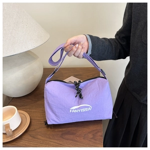 Sac bandoulière en nylon violet clair imperméable tenu par un mannequin au café