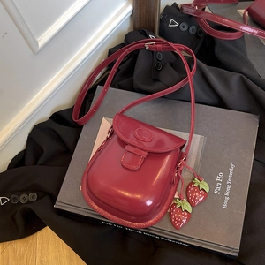Mini borsa a sella rosso scuro in pelle verniciata con ciondoli a fragola e tracolla
