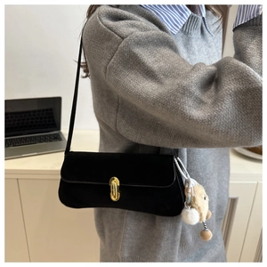 Détail du sac d'épaule en daim noir avec fermoir doré et charmant petit ours en peluche