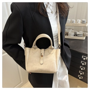 Detail of beige bucket bag with metal buckle and fashion text on textured vegan leather