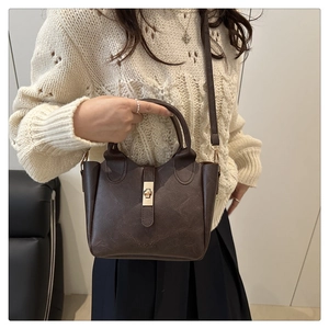 Detail of dark brown faux leather bucket bag with gold twist lock and fashion logo