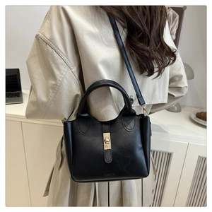 Detail of black leather bucket bag featuring gold twist lock and FASHION embossed logo
