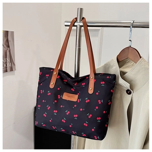 Détail du grand cabas à imprimé cerise avec poignées en cuir marron et rivets dorés