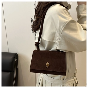 Detail of dark brown suede crossbody bag featuring retro gold clasp and knotted strap