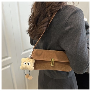 Detail of vintage brown suede baguette bag with gold buckle and star plush pendant