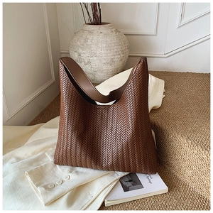 Detail of a dark brown woven hobo bag on a white blazer and vintage magazines