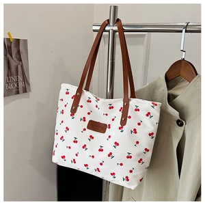 Gros plan sur un sac fourre-tout en toile à cerises avec anses et patch en cuir brun
