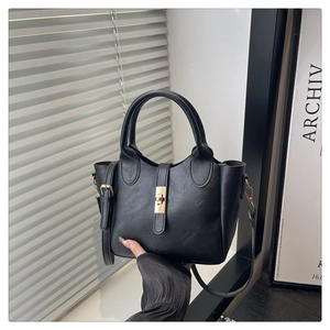 Detail of black matte PU leather bucket bag with gold metal twist lock and thin strap