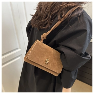 Detail of vintage brown suede shoulder bag featuring a gold twist lock and knotted strap
