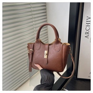 Detail of a brown vintage bucket bag with a gold metal buckle and wave edge design