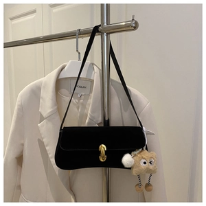 Detail of black baguette shoulder bag with gold metal buckle and cute plush charm
