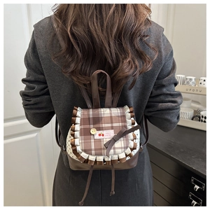 Close-up of a brown plaid mini backpack with ruffled edges and cherry logo tag