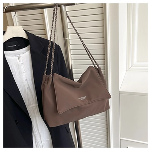 Détail du grand sac cabas marron en cuir avec bandoulière chaîne et texte de mode