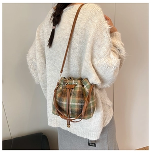 Detalle de bolso saco de cuadros con cordón de cuero y herrajes dorados en una modelo