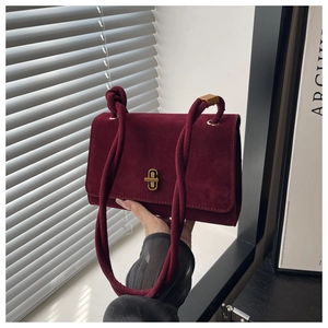 Close-up of wine red suede evening bag with golden rectangular twist lock detail