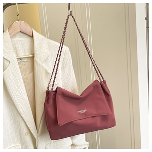 Détail d'un sac bandoulière en cuir vieux rose avec chaîne entrelacée et rabat