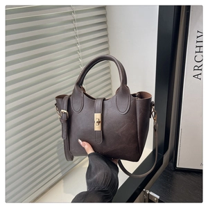 Macro view of vintage dark brown bucket bag showing premium leather texture and gold clasp