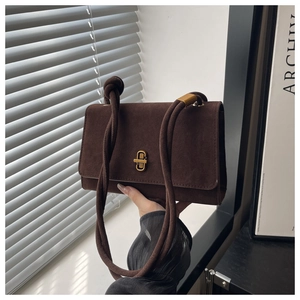 Close-up of retro suede messenger bag with gold twist lock and thick rope shoulder strap