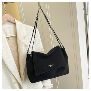 Détail d'un sac bandoulière en cuir noir avec chaîne argentée et lettrage blanc élégant