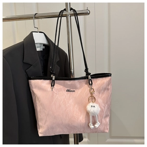 Detailed view of pink tote bag with pleated texture, plush charm and black shoulder straps