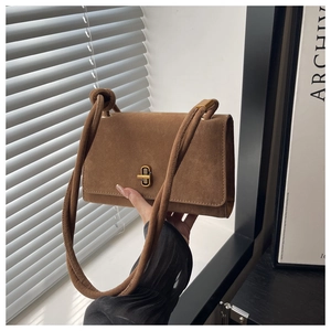 Detail of caramel suede messenger bag featuring premium matte texture and gold twist lock