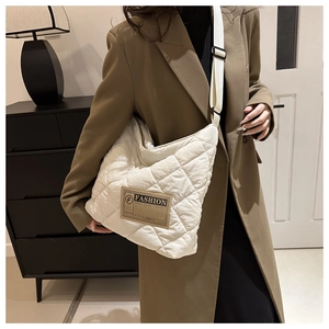 Detail of the white quilted diamond texture and brown fashion patch on the tote bag