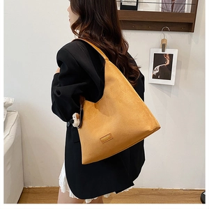 Détail du sac cabas en daim moutarde avec pendentif peluche et large bandoulière