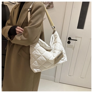Détail du sac fourre-tout matelassé blanc avec étiquette marron et large bandoulière