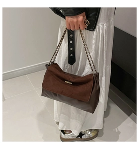 Close-up of brown dual-material shoulder bag with chain strap and gold hardware detail