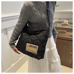 Close-up of black quilted nylon tote bag with fashion label and wide shoulder strap