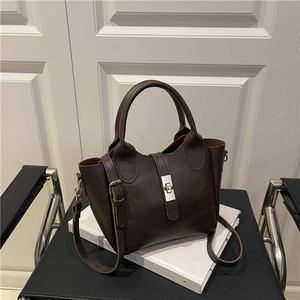 Minimalist dark brown bucket bag with retro texture and metal buckle on a black leather chair