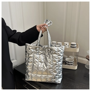 Close-up of silver quilted tote bag showing metallic texture and puffy vertical padding