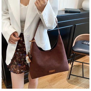 Détail d'un grand sac hobo en daim marron avec étiquette de mode et breloque chiot