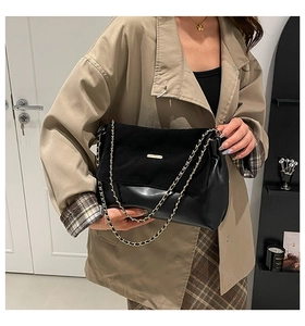 Detail of the black patchwork chain strap and textured suede flap on the shoulder bag