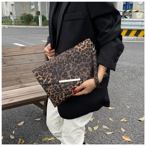 Dettaglio pochette a busta leopardata con finiture dorate e cinturino da polso rimovibile