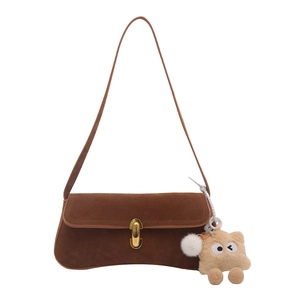 Brown faux suede underarm bag with gold U-buckle and cute plush charms on a white background