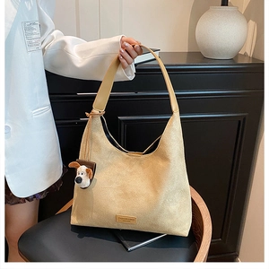 Détail du sac hobo en daim beige avec large bandoulière et breloque chien en peluche