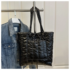 Detailed view of black quilted puffer tote bag with vertical stitching and front pocket