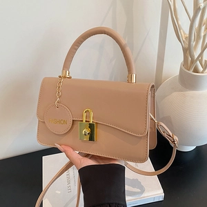 Schicke beige Umhängetasche mit Goldschloss und Griff in Lifestyle-Umgebung präsentiert
