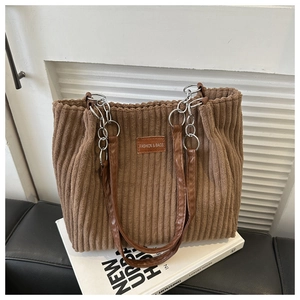 Detail of brown corduroy tote bag featuring silver chain strap and fashion label