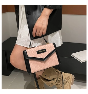 Detail of pink woven texture and black leather trim on a stylish crossbody bag