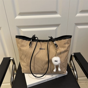 Large khaki tote bag with crinkle texture and a cute white fuzzy monster charm