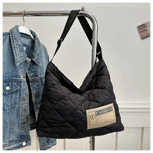 Détail d'un grand sac fourre-tout matelassé noir avec étiquette mode et sangle