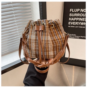 Detalle de bolso cubo de lana a cuadros con cordón de cuero y detalles metálicos dorados