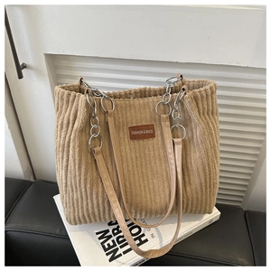 Detail of khaki corduroy tote bag featuring a leather patch and silver chain strap
