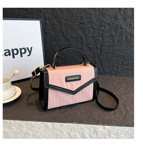 Detail of woven texture design on pink and black crossbody bag with logo badge
